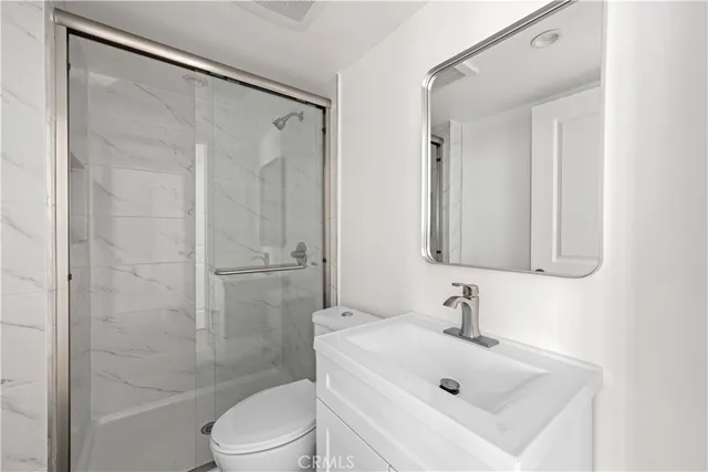 a bathroom with a toilet sink vanity and shower