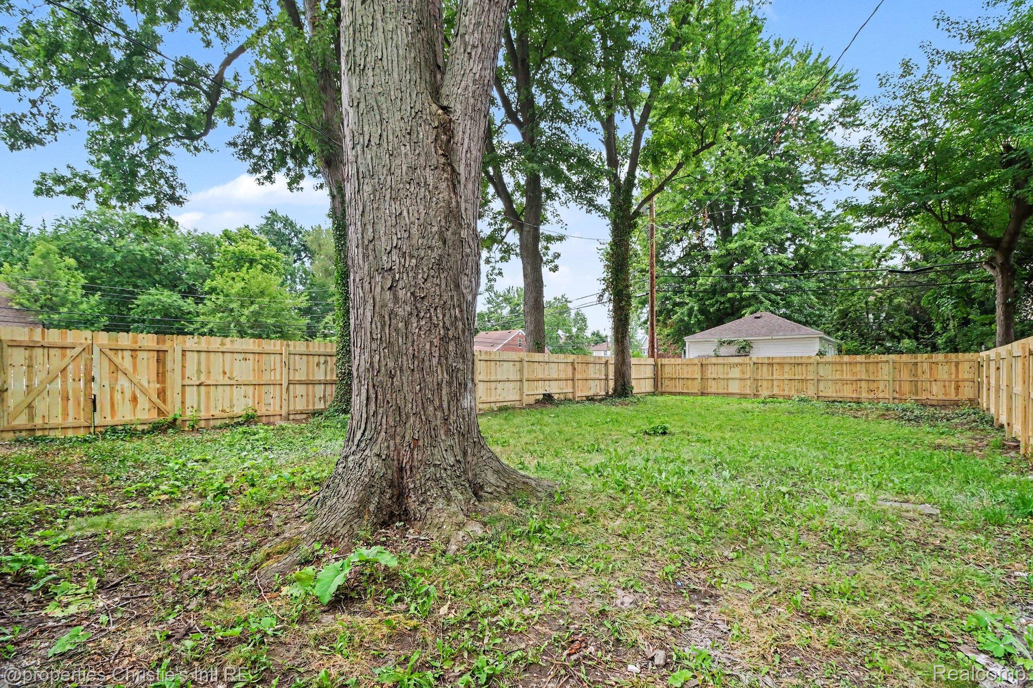 5911 Yorkshire Road Detroit, MI 48224 - Photo 14 of 14 Spacious backyard featuring a large mature tree, newly installed wood privacy fencing, and a wood gate