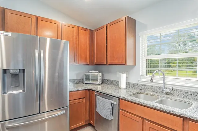 a kitchen with granite countertop stainless steel appliances a refrigerator sink and cabinets