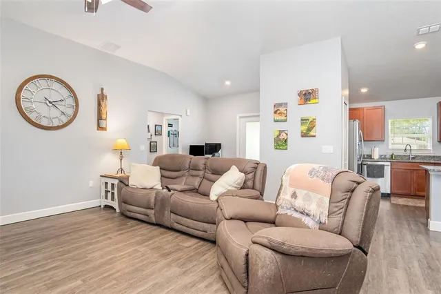 a living room with furniture a clock on wall and a window
