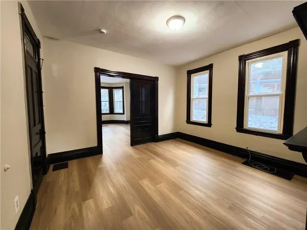 an empty room with wooden floor and windows