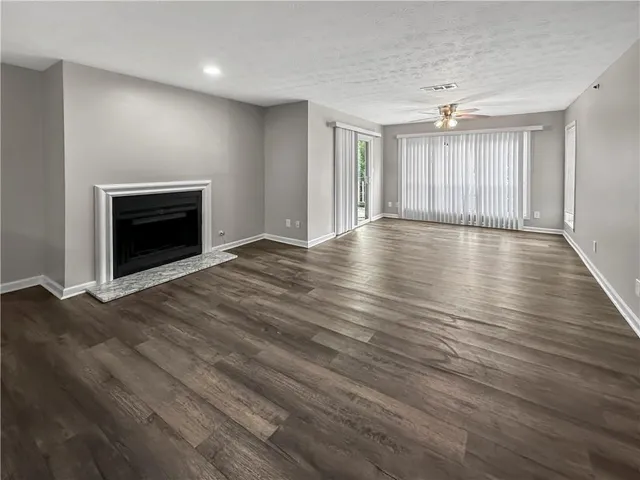 a view of an empty room with wooden floor fireplace and a window