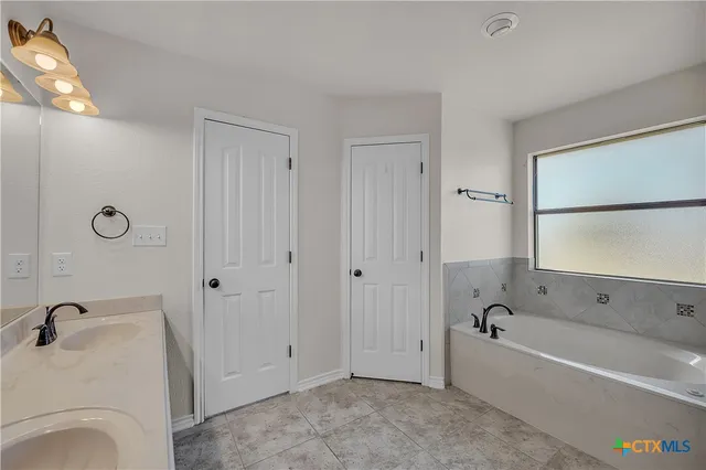 a bathroom with a tub a sink and a window