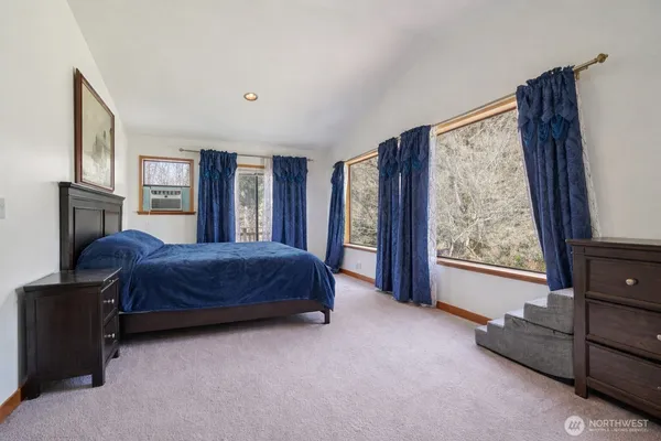 a spacious bedroom with a large bed and a dresser next to a window