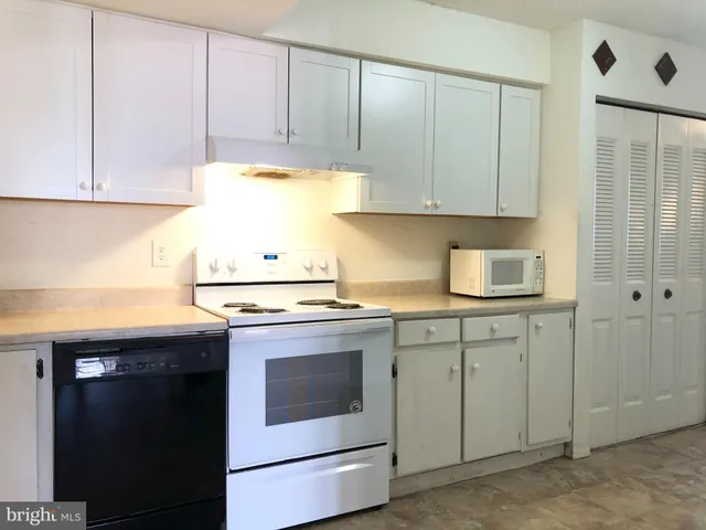 a kitchen with granite countertop white cabinets and white appliances