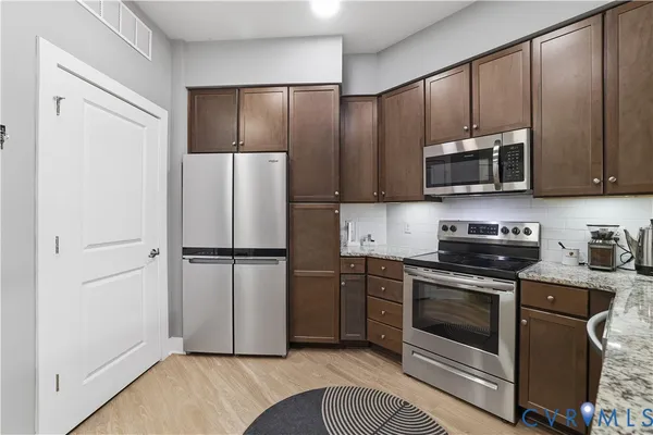 a kitchen with stainless steel appliances granite countertop a stove a refrigerator and a microwave
