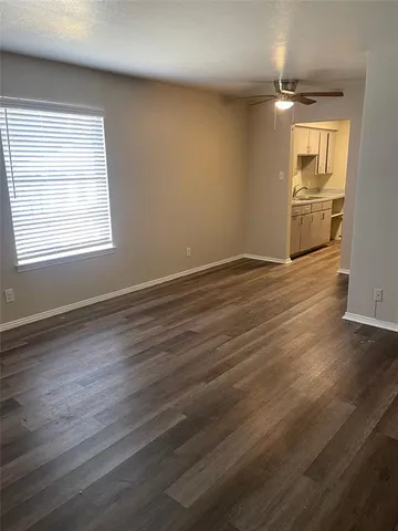 an empty room with wooden floor cabinet and windows