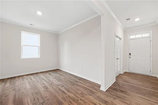 a view of an empty room with wooden floor and a window