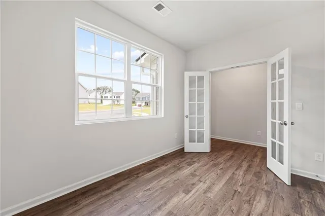 an empty room with wooden floor cabinet and windows