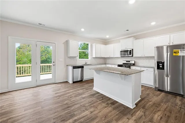 a kitchen with white cabinets and wooden floor