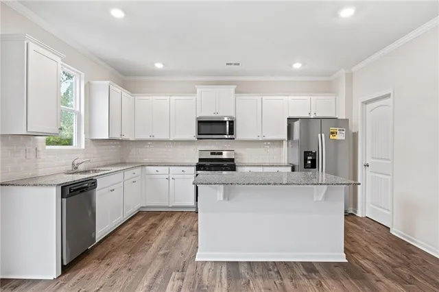 a kitchen with stainless steel appliances granite countertop a stove top oven a refrigerator a sink and dishwasher with wooden floor