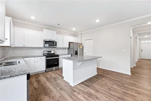 a kitchen with stainless steel appliances white cabinets a sink a stove a refrigerator and microwave