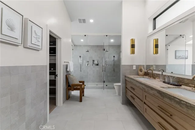 a bathroom with a double vanity sink a toilet a mirror and shower