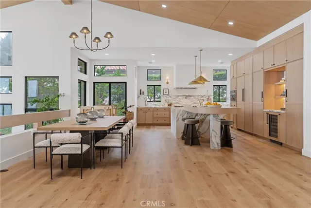 a kitchen with stainless steel appliances granite countertop a stove top oven a sink dishwasher a dining table and chairs with wooden floor