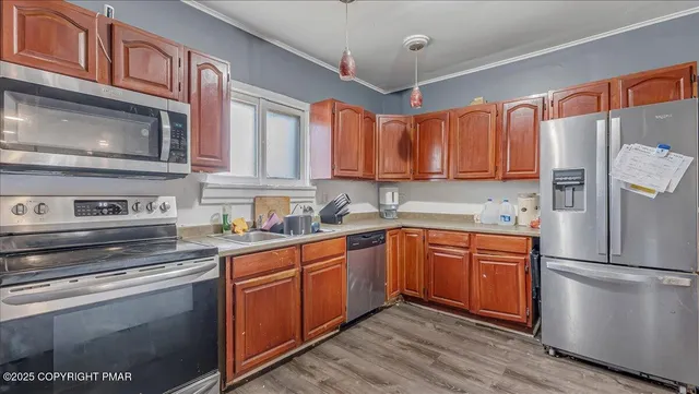 a kitchen with stainless steel appliances granite countertop a refrigerator a sink dishwasher a stove and white countertops with wooden floor