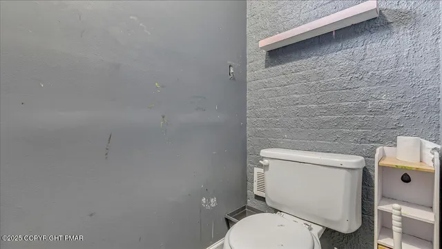 a white toilet sitting next to a white wall