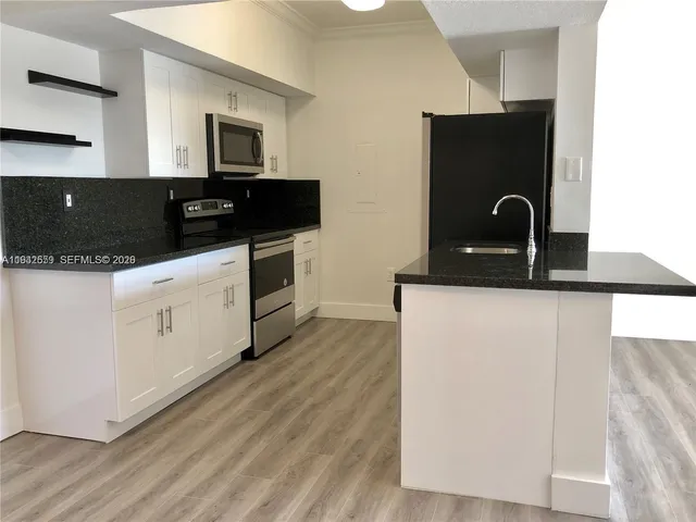 a kitchen with granite countertop a refrigerator and a stove top oven