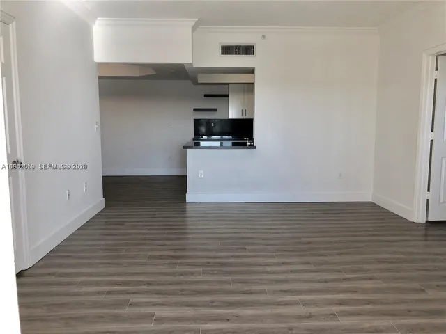 a view of kitchen and empty room with wooden floor