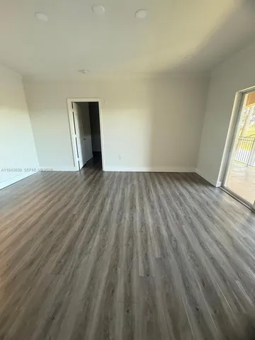 a view of an empty room and wooden floor and window