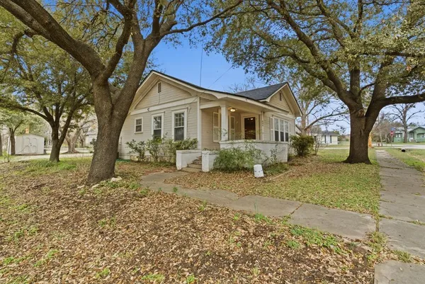 a front view of a house with a garden and trees