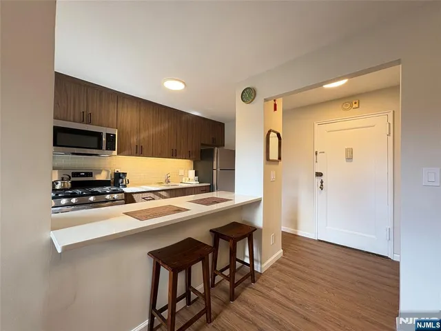 a kitchen with stainless steel appliances granite countertop a refrigerator a sink dishwasher and wooden cabinets with wooden floor