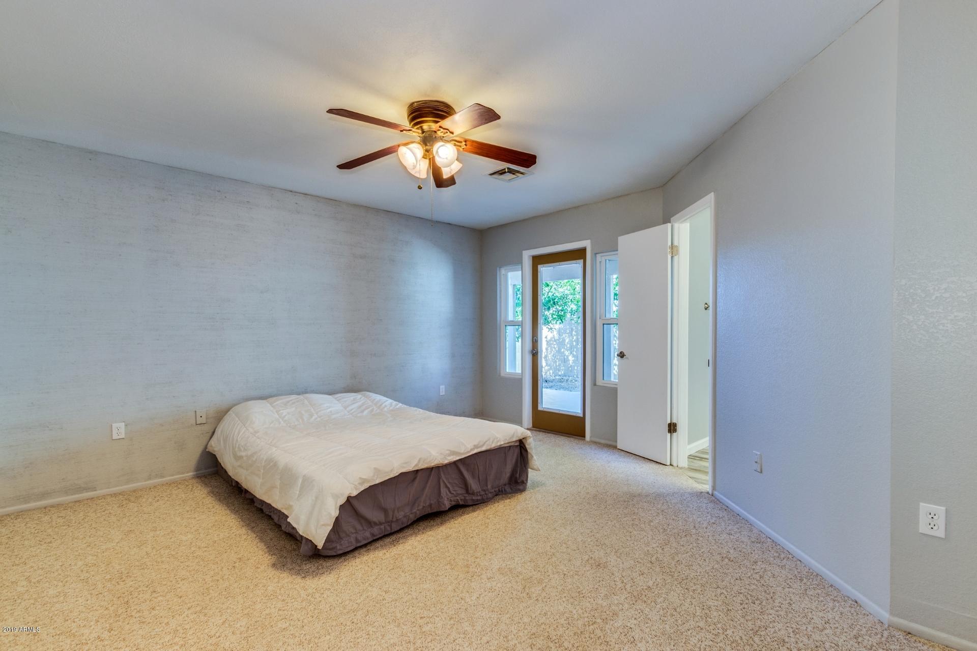 4812 East Gary Street Mesa, AZ 85205 - Photo 27 of 37 a spacious bedroom with a bed and a chandelier