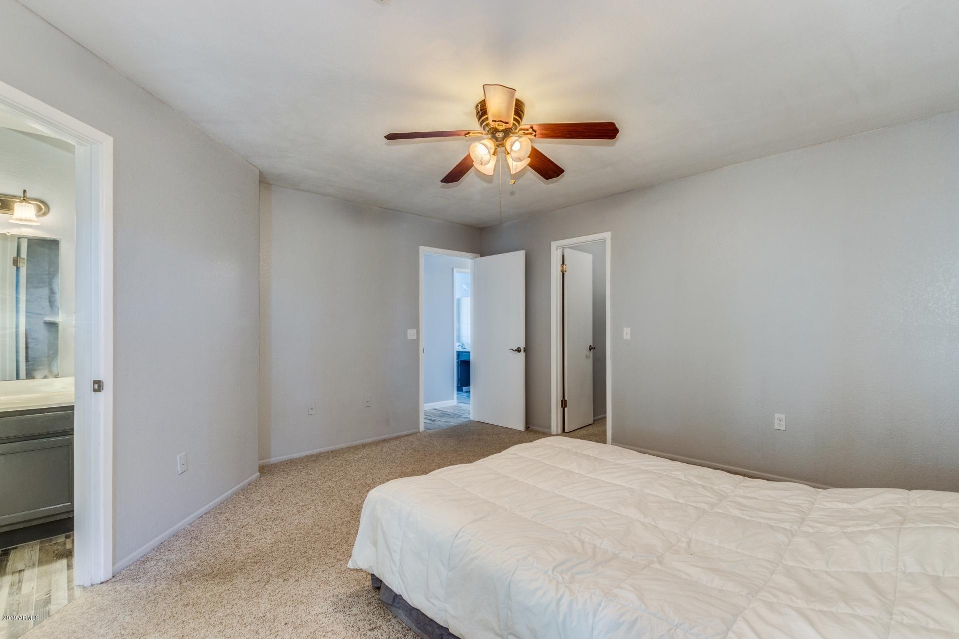 4812 East Gary Street Mesa, AZ 85205 - Photo 29 of 37 a bedroom with a large bed and a chandelier