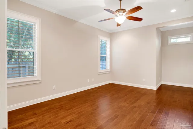 a view of empty room with wooden floor and fan