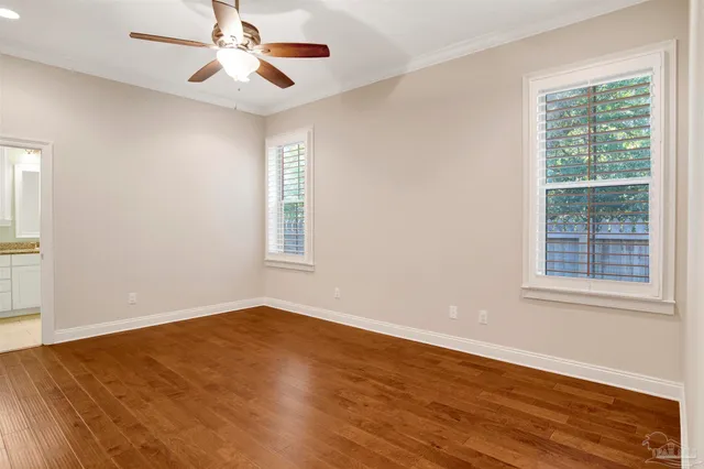 an empty room with wooden floor ceiling fan and windows