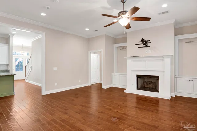 a view of an empty room with wooden floor fireplace and a window