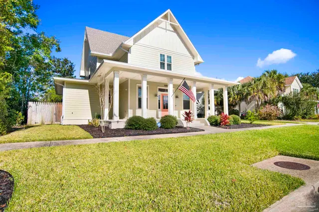 a view of a white house with a yard and potted plants