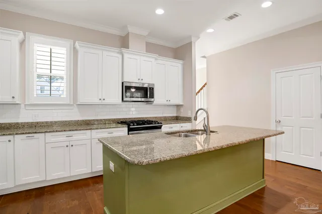 a kitchen with granite countertop a sink a stove and cabinets