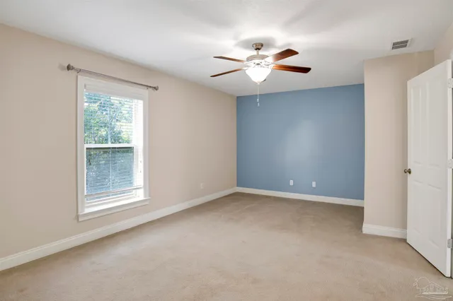 an empty room with windows and fan