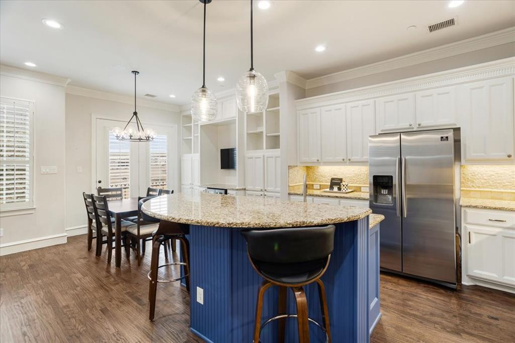 7940 Bishop Road Plano, TX 75024 - Photo 21 of 36 a kitchen with stainless steel appliances granite countertop a kitchen island a stove a refrigerator a sink a dining table and chairs with wooden floor