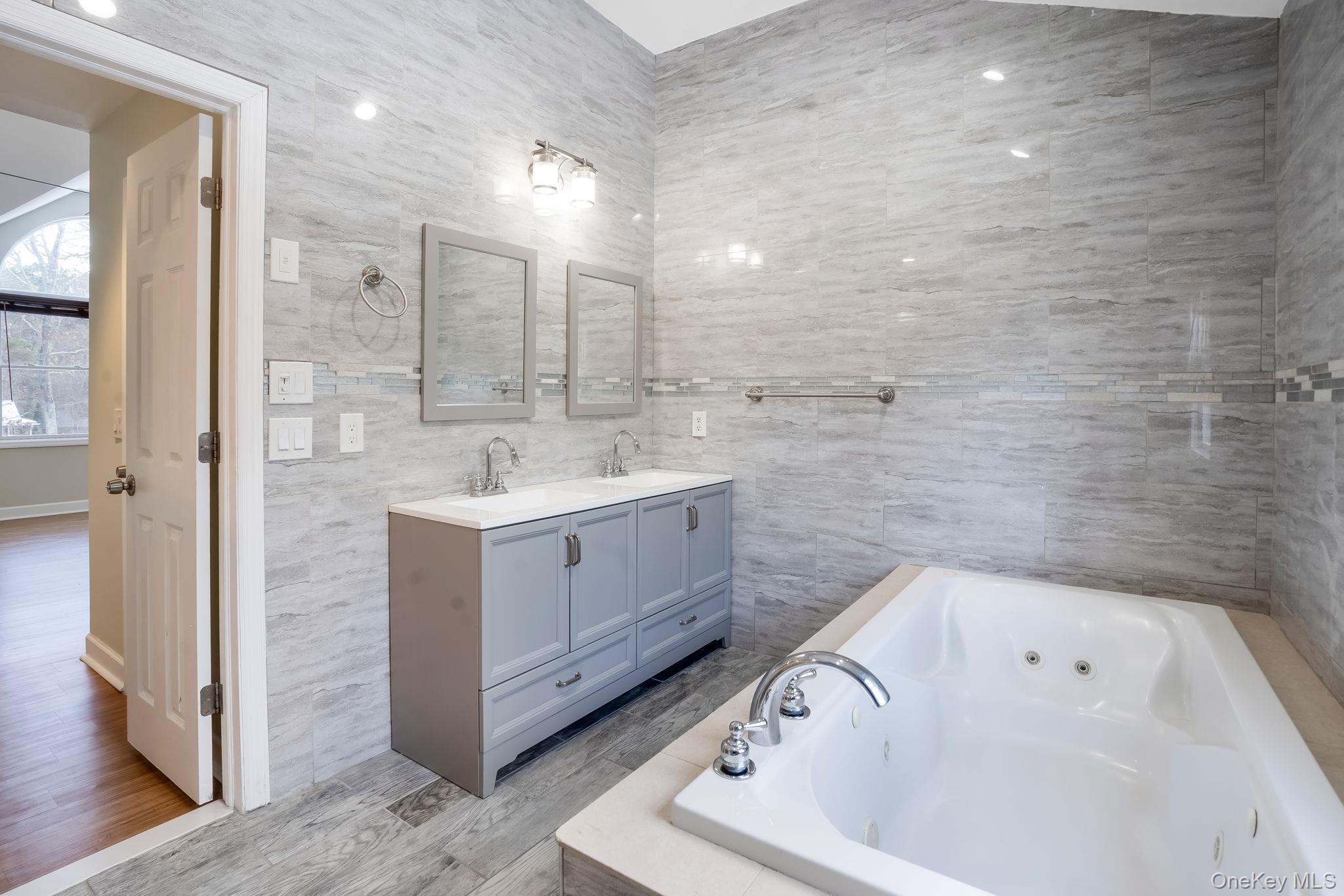 400 Eastport Manor Road Manorville, NY 11949 - Photo 18 of 29 a bathroom with a bathtub sink mirror and vanity
