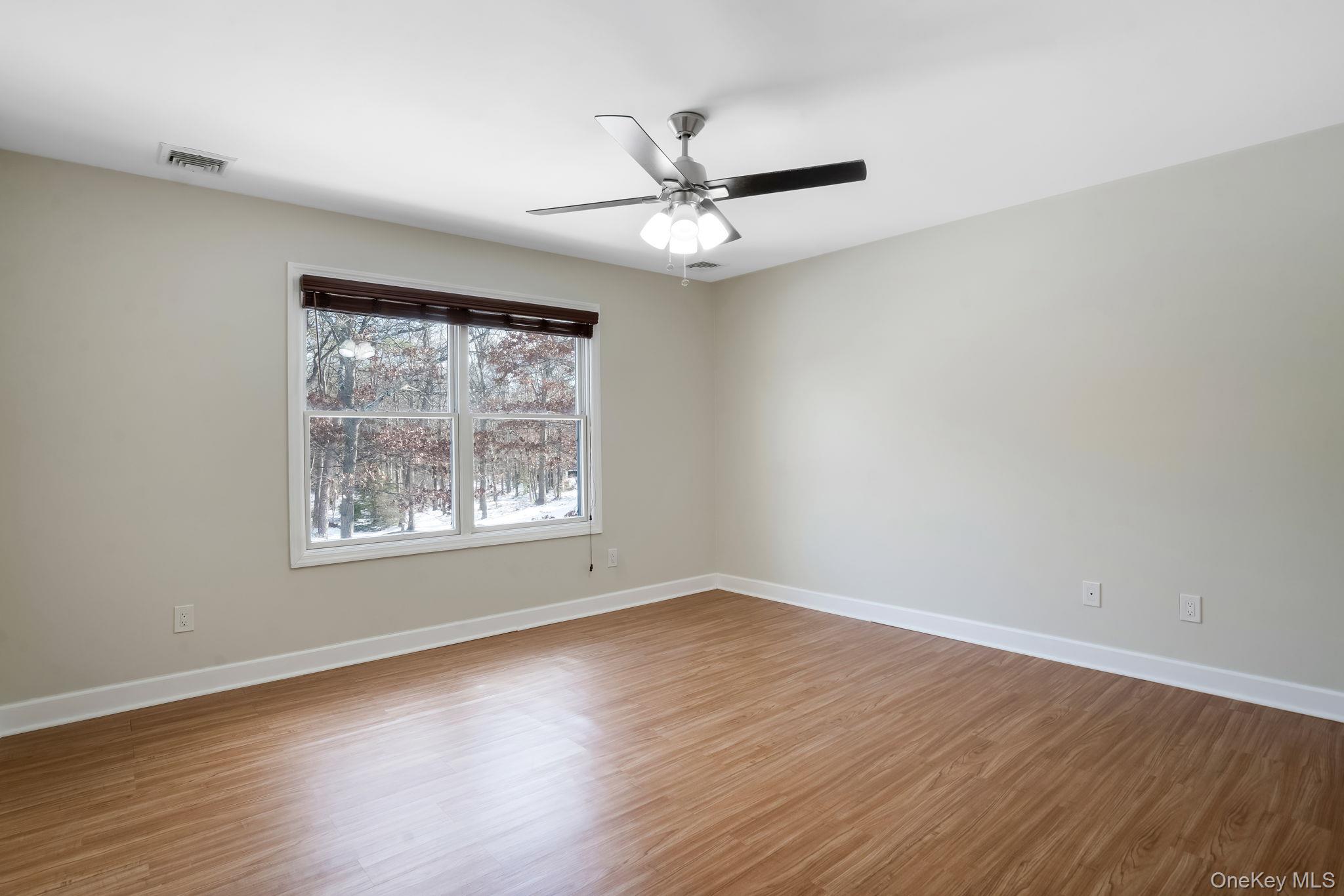 400 Eastport Manor Road Manorville, NY 11949 - Photo 20 of 29 a view of an empty room with wooden floor and a window