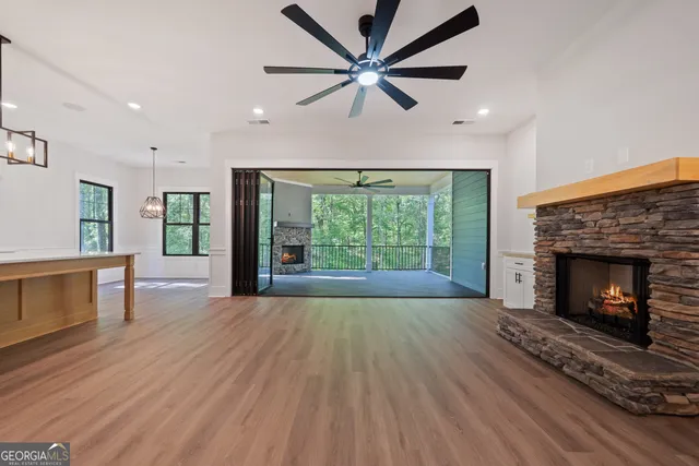 a view of an empty room with wooden floor and a ceiling fan