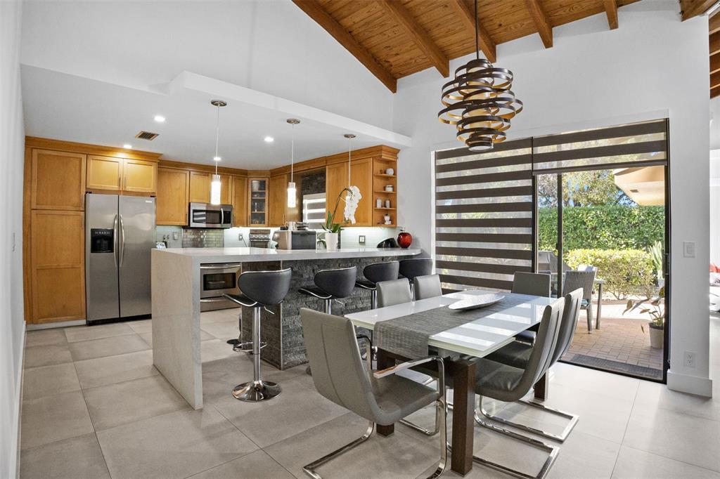 8125 Royal Palm Court, Unit 2 Tamarac, FL 33321 - Photo 7 of 35 a kitchen with stainless steel appliances kitchen island granite countertop a table chairs in it and wooden floors