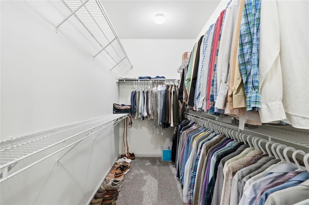 1114 Firethorne Pass Cumming, GA 30040 - Photo 21 of 43 a view of walk in closet with clothes and shoes