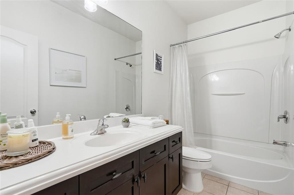 1114 Firethorne Pass Cumming, GA 30040 - Photo 27 of 43 a bathroom with a granite countertop sink toilet a large mirror a shower and vanity