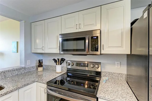 a kitchen with stainless steel appliances granite countertop white cabinets and a stove a oven with white countertops