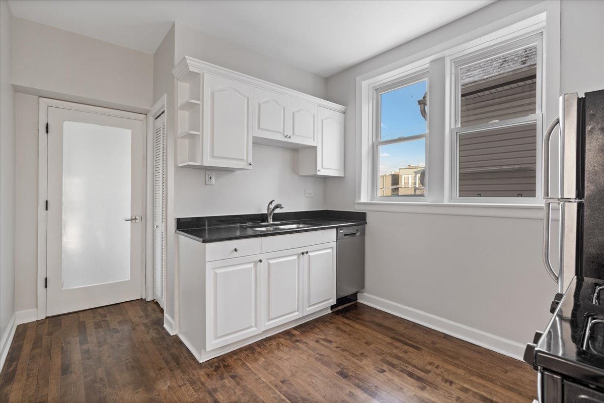 2338 North Avers Avenue, Unit 2 Chicago, IL 60647 - Photo 8 of 23 a kitchen with stainless steel appliances granite countertop a stove a sink and white cabinets with wooden floor