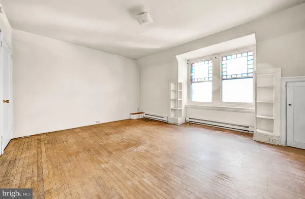an empty room with wooden floor and window