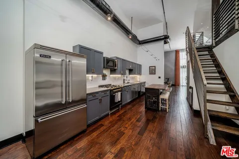 a kitchen with stainless steel appliances a refrigerator a stove and a wooden floor