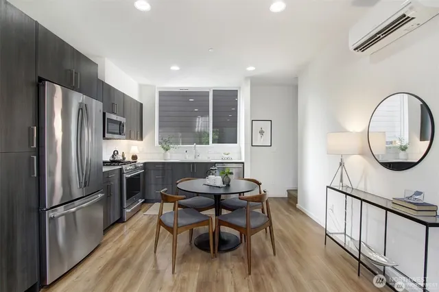 a kitchen with stainless steel appliances granite countertop a dining table chairs refrigerator and sink