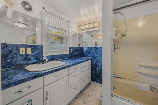 a spacious bathroom with a granite countertop sink mirror and a shower