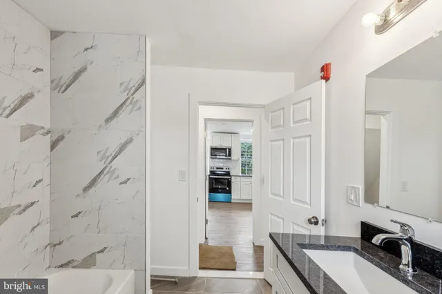 a bathroom with a granite countertop sink a mirror and shower