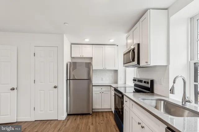 a kitchen with stainless steel appliances granite countertop a refrigerator sink and white cabinets