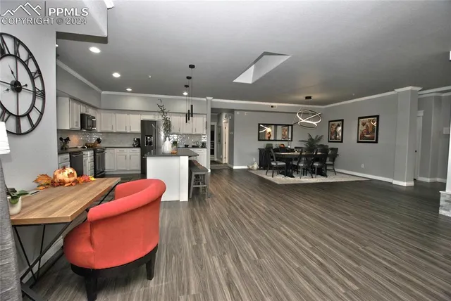 a kitchen with stainless steel appliances kitchen island granite countertop a stove a refrigerator and a dining table with wooden floor