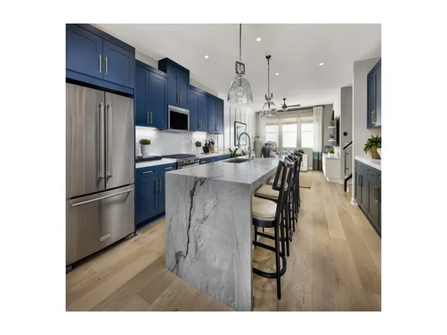 a kitchen with stainless steel appliances a refrigerator a stove a sink dishwasher and a dining table with wooden floor